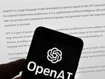 The OpenAI logo is seen on a mobile phone in front of a computer screen which displays output from ChatGPT. The OpenAI logo is seen on a mobile phone in front of a computer screen which displays output from ChatGPT.