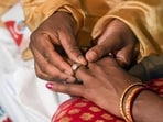A groom puts a ring on his bride's finger.