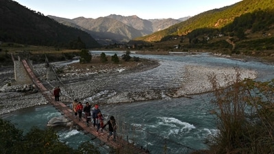 (FILES) This photograph taken on December 6, 2019 shows tourists walking across a suspension bridge over the Puna Tsang Chhu River in Punakha province in Bhutan. Squeezed between giant arch-rivals India and China, the landlocked mountain kingdom of Bhutan was long isolated by icy Himalayan peaks. But as Bhutan readies to elect a new parliament in Thimphu on January 9, China and India are watching the contest with keen interest as they eye strategic contested border zones, analysts warn. (Photo by Lillian SUWANRUMPHA / AFP) (AFP) (FILES) This photograph taken on December 6, 2019 shows tourists walking across a suspension bridge over the Puna Tsang Chhu River in Punakha province in Bhutan. Squeezed between giant arch-rivals India and China, the landlocked mountain kingdom of Bhutan was long isolated by icy Himalayan peaks. But as Bhutan readies to elect a new parliament in Thimphu on January 9, China and India are watching the contest with keen interest as they eye strategic contested border zones, analysts warn. (Photo by Lillian SUWANRUMPHA / AFP) (AFP)