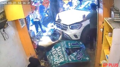 Man in yellow shirt frantically searching for his wife under the Mercedes that the Noida lawyer rammed into a popular Delhi shop. (X/@GabbbarSingh) Man in yellow shirt frantically searching for his wife under the Mercedes that the Noida lawyer rammed into a popular Delhi shop. (X/@GabbbarSingh)
