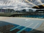This photograph taken on March 28, 2024 via a window, shows swimming pools in the Aquatics Centre built for the Paris 2024 Olympic Games to be used for artistic swimming, diving and water polo competitions in Saint Denis, near Paris. VenhoevenCS & Ateliers 2/3/4/ designed the building. The Seine-Saint-Denis department north of Paris will host a number of events for the Paris 2024 Olympic and Paralympic Games, with venues including the Stade de France and Aquatics Centre, as well as the Olympic Village. (Photo by Dimitar DILKOFF / AFP) This photograph taken on March 28, 2024 via a window, shows swimming pools in the Aquatics Centre built for the Paris 2024 Olympic Games to be used for artistic swimming, diving and water polo competitions in Saint Denis, near Paris. VenhoevenCS & Ateliers 2/3/4/ designed the building. The Seine-Saint-Denis department north of Paris will host a number of events for the Paris 2024 Olympic and Paralympic Games, with venues including the Stade de France and Aquatics Centre, as well as the Olympic Village. (Photo by Dimitar DILKOFF / AFP)