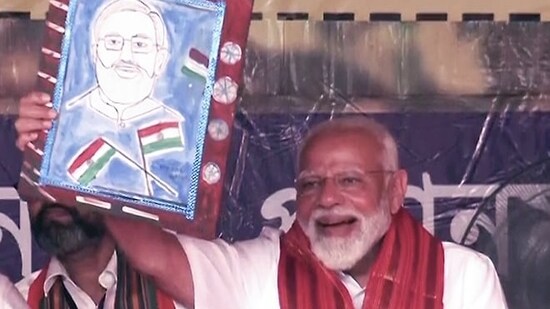 PM Narendra Modi carries a portrait of himself during a public rally ahead of the Lok Sabha elections, in Cooch Behar.(ANI)