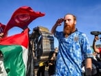 People wave Palestinian and Tunisian flags while British runner Russ Cook gestures as he poses for a picture with the memorial sign marking the northern-most point of Africa 