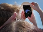 A couple uses a cell phone to photograph the solar eclipse on the campus of Southern Illinois University on April 08, 2024, in Carbondale, Illinois.