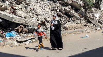 A woman and boy walk past the rubble of a collapsed building along a street in Rafah in the southern Gaza Strip (AFP) A woman and boy walk past the rubble of a collapsed building along a street in Rafah in the southern Gaza Strip (AFP)