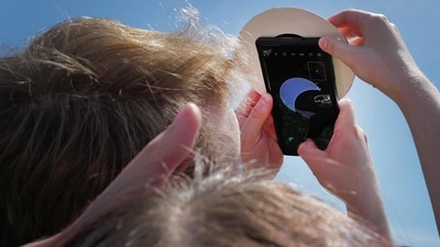 A couple uses a cell phone to photograph the solar eclipse on the campus of Southern Illinois University on April 08, 2024, in Carbondale, Illinois. ( AFP)