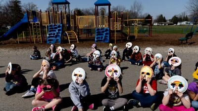 Students from two kindergarten classes, escorted outside by their teachers, stare toward the sky with their specially-made glasses to watch the solar eclipse on Monday. (AP) Students from two kindergarten classes, escorted outside by their teachers, stare toward the sky with their specially-made glasses to watch the solar eclipse on Monday. (AP)