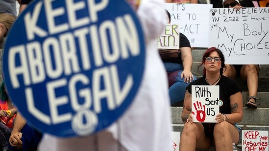 Protesters hold signs as Barbara DeVane, of the Tallahassee National Organization for Women, speaks outside the Florida Historic Capitol (AP)