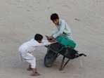 Children balance a wheelbarrow with water jerrycans, which they filled from a nearby hand pump, as they head home in Karachi, Pakistan (File)