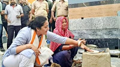 Ghaziabad’s Congress candidate Dolly Sharma trying her hands at making chapatis on a chulha (earthen stove) at Bhoopkhedi village in Ghaziabad's Loni during her campaigning. (HT Photo)
