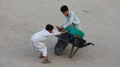 Children balance a wheelbarrow with water jerrycans, which they filled from a nearby hand pump, as they head home in Karachi, Pakistan (File) (REUTERS)