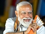 Prime Minister Narendra Modi holds the party symbol during a road show at an election campaign on April 9.(AFP)