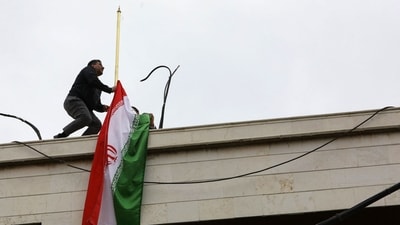 A staff member sets up the Iranian flag atop a new consular annex to Iran's embassy in Damascus on its inauguration day on April 8, 2024.(Photo by LOUAI BESHARA / AFP)