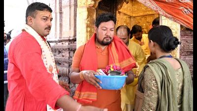 Police personnel dressed as priests assist a devotee at the Kashi Vishwanath Temple. (ANI Photo)