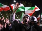 Demonstrators wave Iran's flag and Palestinian flags as they gather in front of the British embassy in Tehran on April 14, 2024, after Iran launched a drone and missile attack on Israel. 