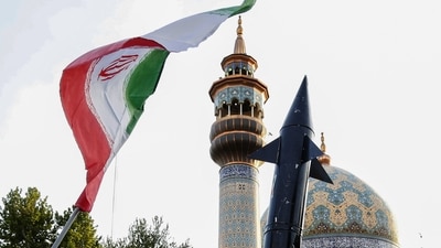 Iranian lift up a flag and the mock-up of a missile during a celebration following Iran's missiles and drones attack on Israel, on April 15 2024, at Palestine square in central Tehran. (AFP)