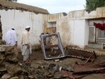 A man removes a window frame inside the debris of a damaged house following a flash flood in Gulgad village in Lal Pur district of Nangarhar province