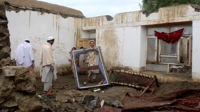 A man removes a window frame inside the debris of a damaged house following a flash flood in Gulgad village in Lal Pur district of Nangarhar province (REUTERS)