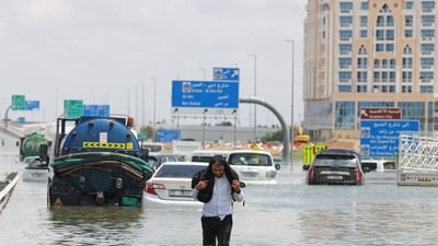 A driver walks along a flooded highway after a rainstorm in Dubai, United Arab Emirates, on Wednesday (Bloomberg) A driver walks along a flooded highway after a rainstorm in Dubai, United Arab Emirates, on Wednesday (Bloomberg)