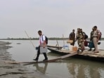 An election official carrying an Electronic Voting Machine (EVM) to a polling station, disembarks a boat on the eve of the first round of voting at Lohore Chapori in Golaghat, Assam.(AFP)