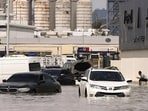 A person sits near vehicles stranded in flood water caused by heavy rains in Dubai, United Arab Emirates, April 17, 2024.