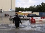 A person walks towards cars stranded in flood water caused by heavy rains, in Dubai.
