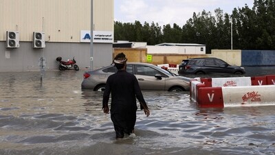 A person walks towards cars stranded in flood water caused by heavy rains, in Dubai. (REUTERS)