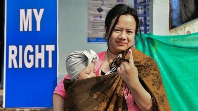 A voter carrying her child shows her finger marked with ink after casting her vote, in Meghalaya. (PTI)