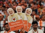 A supporter of Bharatiya Janata Party (BJP) holds cutouts of Prime Minister Narendra Modi during an election campaign where Modi speaks, in Bengaluru.