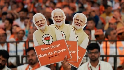 A supporter of Bharatiya Janata Party (BJP) holds cutouts of Prime Minister Narendra Modi during an election campaign where Modi speaks, in Bengaluru. (REUTERS)