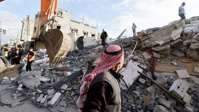 A passerby looks on as Palestinians inspect the site of an Israeli strike on a house, amid the ongoing conflict between Israel and the Palestinian Islamist group Hamas, in Rafah, in the southern Gaza Strip, April 21, 2024. (REUTERS)