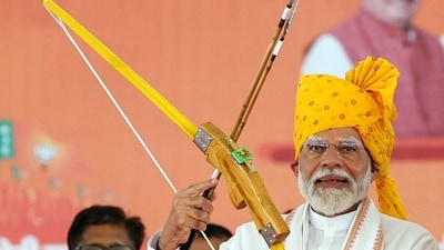 Prime Minister Narendra Modi holds a bow and an arrow during a public meeting in support of BJP candidate Mahendrajeet Singh Malviya for the Lok Sabha polls, in Banswara on Sunday. (BJP)