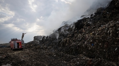 A firefighter works to douse fire as smoke billows from burning garbage at the Ghazipur landfill site in New Delhi (REUTERS)