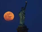 Pink Moon captured behind the Statue of Liberty in New York City.