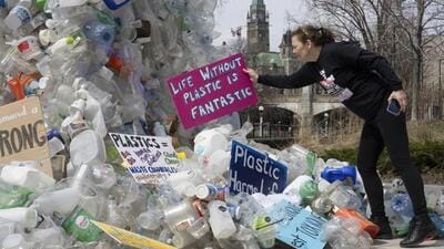 Activist Dianne Peterson places a sign on a public art installation outside a United Nations conference on plastics on April 23 (AP)