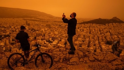 A man takes a photograph of the city of Athens from Tourkovounia hill, as southerly winds carry waves of Saharan dust to the city, in Athens. (AFP) A man takes a photograph of the city of Athens from Tourkovounia hill, as southerly winds carry waves of Saharan dust to the city, in Athens. (AFP)