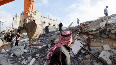 A passerby looks on as Palestinians inspect the site of an Israeli strike on a house, amid the ongoing conflict between Israel and the Palestinian Islamist group Hamas, in Rafah, in the southern Gaza Strip, April 21, 2024. (REUTERS)
