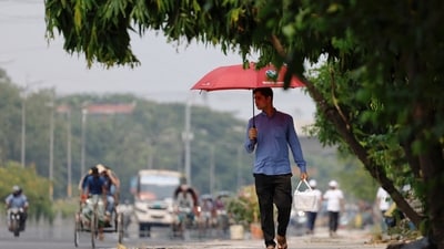 A man walks along a road with an umbrella to cover himself from the sun during a countrywide heatwave in Dhaka, Bangladesh. (REUTERS)