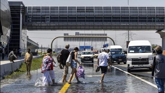People walk through floodwater caused by heavy rain while waiting for transportation on Sheikh Zayed Road highway in Dubai, United Arab Emirates, on April 18. A new report says climate change played a role in the floods. (AP)