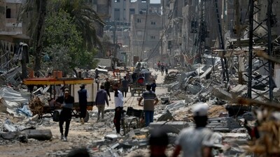 Palestinians walk amid the rubble of destroyed buildings in Nuseirat, in the central Gaza Strip (AFP)