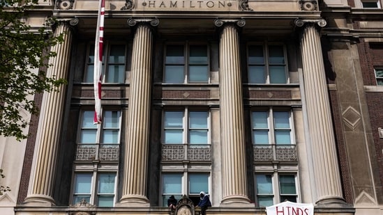 Pro-Palestinian protesters who are occupying Hamilton Hall sit on a ledge as they look at a crowd at Columbia University on April 30, 2024 in New York City. Columbia University had restricted access to the school's campus to students residing in residential buildings on campus and employees who provide essential services to campus buildings after protestors took over Hamilton Hall overnight renaming it as "Hind's Hall" in honor of Hind Rajab.&nbsp;(Getty Images via AFP)