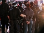FILE - As light rain falls, New York City police officers take people into custody near the Columbia University campus in New York, Tuesday, April 30, 2024, after a building taken over by protesters earlier in the day was cleared, along with a tent encampment. (AP Photo/Craig Ruttle, File)