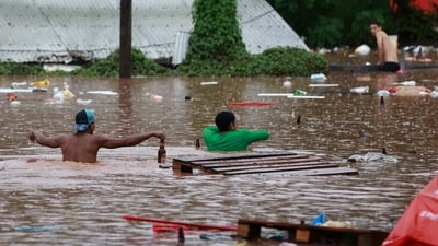 People walk in a flooded area next to the Taquari River during heavy rains in Encantado, Rio Grande do Sul state, Brazil. (REUTERS)