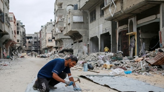 A Palestinian man fixes tin sheets used for temporary sheltering on a road lined with destroyed buildings in Khan Yunis in the southern Gaza Strip on May 2, 2024, amid the ongoing conflict between Israel and the Hamas movement. (AFP)