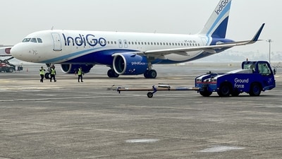 Ground staff walk past an Indigo airlines aircraft taxiing in the apron at the Netaji Subhash Chandra Bose International airport in Kolkata on February 1, 2024. (AFP) (AFP)