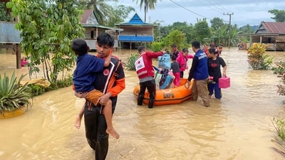 Rescuers carry people affected by a flood in Wajo, South Sulawesi, Indonesia. (AP)