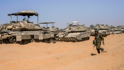 An Israeli soldier walks past a line of tanks at a staging ground near the border with the Gaza Strip, in southern Israel, Sunday, (AP) An Israeli soldier walks past a line of tanks at a staging ground near the border with the Gaza Strip, in southern Israel, Sunday, (AP)
