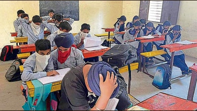 Students of Bassian Bet government school tie handkerchiefs on their face to shield against the smell emanating from the nearby poultry farm (below) in Ludhiana on Monday. (Manish/HT)