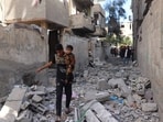 Palestinian youth carries a child as he walks through the rubble following Israeli bombardment of Rafah's Tal al-Sultan district in the southern Gaza Strip on May 7, 2024. The Israeli army said it took 