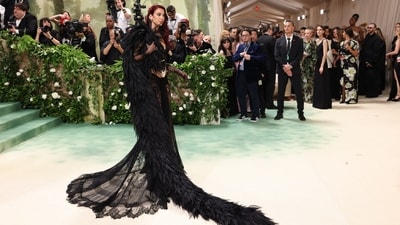 Dua Lipa made a striking entrance on the Met Gala carpet, donning a lacy all-black ensemble by Marc Jacobs. Her outfit featured a corset layered beneath delicate lace, paired with a gathered see-through lace maxi skirt. She accessoried with coordinating mesh polka-dot opera gloves, layers of bedazzled belly chains, and a spiked diamond-encrusted necklace. However, the focal point was undoubtedly the massive feathered cape draped over one shoulder.&nbsp; (REUTERS)